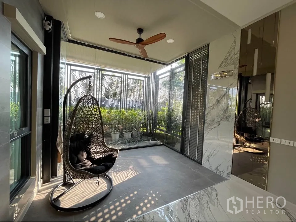 บ้านเดี่ยว for rent or sale in Bang Phli, Samut Prakan - ซันรูมหรือเฉลียงปิดล้อมพร้อมเก้าอี้แขวนและพัดลมเพดาน