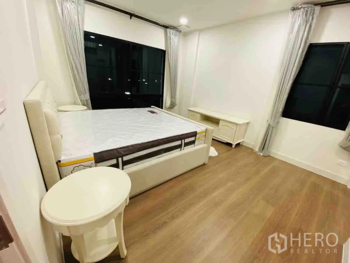 Detached House for rent or sale in Saphan Sung, Bangkok - Corner bedroom with double windows, neutral drapes and wood floors