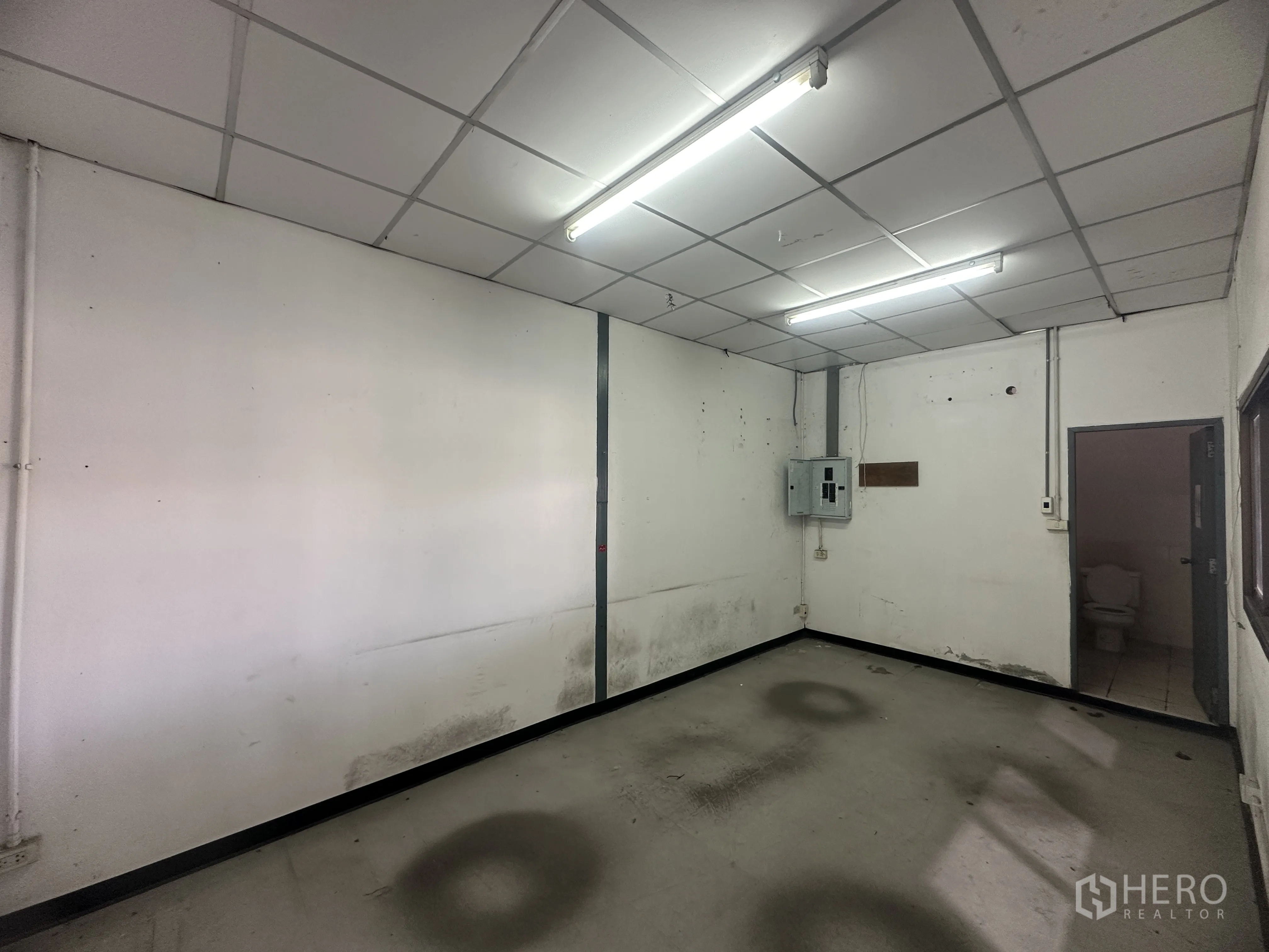 仓库 for rent in Khlong Luang, Pathum Thani - 简洁办公房，配有日光灯，旁侧为卫生间门。