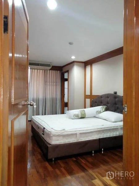 Condominium for rent in Watthana, Bangkok - Bedroom with bed, curtains and warm wood trim.