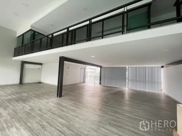 Office Space for rent in Bang Na, Bangkok - Open-plan lower floor beneath mezzanine with wide windows, vertical blinds and wood-look flooring.