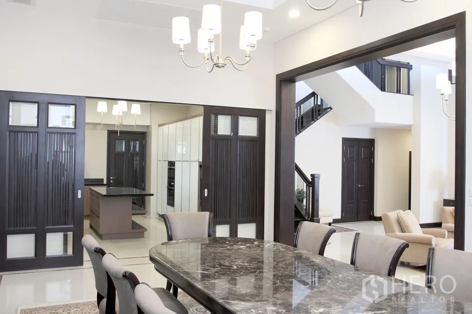 Detached House for rent in Khlong Toei, Bangkok - Spacious dining area with sliding wood doors opening to a modern kitchen island and living space.
