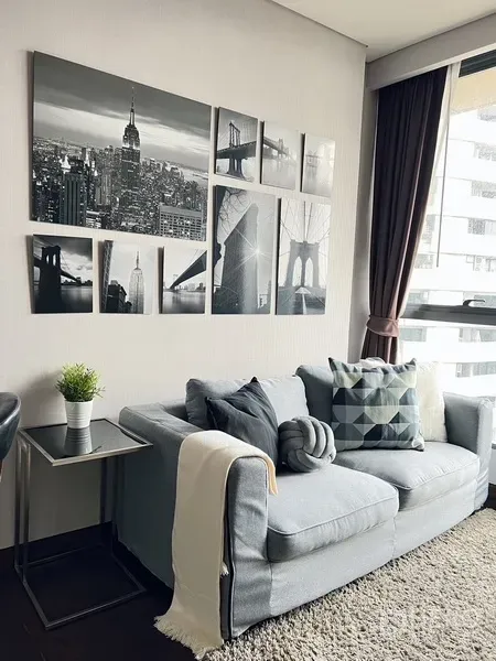 คอนโด ให้เช่าหรือขายในKhlong Toei, Bangkok - โซฟาสีเทาอบอุ่นใต้ภาพศิลป์เมืองขาวดำ ข้างหน้าต่างบานใหญ่พร้อมผ้าม่าน