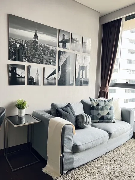 คอนโด ให้เช่าหรือขายในKhlong Toei, Bangkok - โซฟาสีเทาอบอุ่นใต้ภาพศิลป์เมืองขาวดำ ข้างหน้าต่างบานใหญ่พร้อมผ้าม่าน