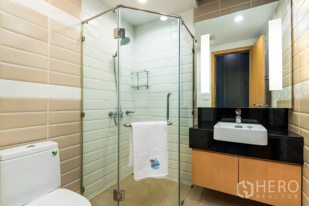 公寓 出租在Ratchathewi, Bangkok - 卫浴间配玻璃淋浴房、洗手台与坐便器。