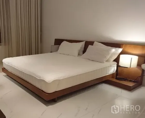 คอนโด ให้เช่าในPathum Wan, Bangkok - ห้องนอนกว้าง เตียงคิงส์ไซซ์แบบแพลตฟอร์ม หัวเตียงไม้ โคมไฟข้างเตียง และพื้นกระเบื้องใหญ่