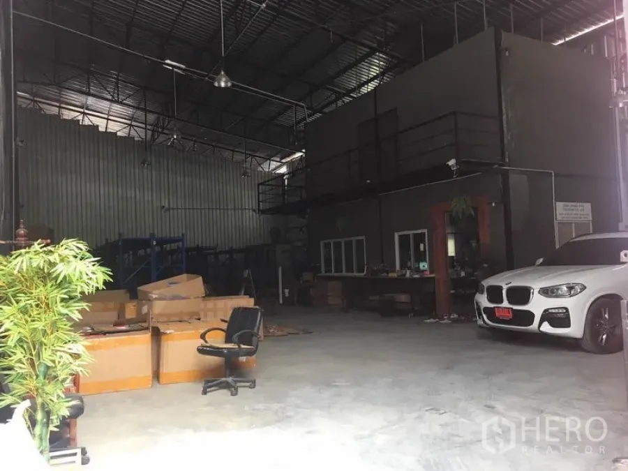 Warehouse for rent in Bang Kapi, Bangkok - Spacious high-ceiling warehouse interior with mezzanine office, concrete floor and parking bay.