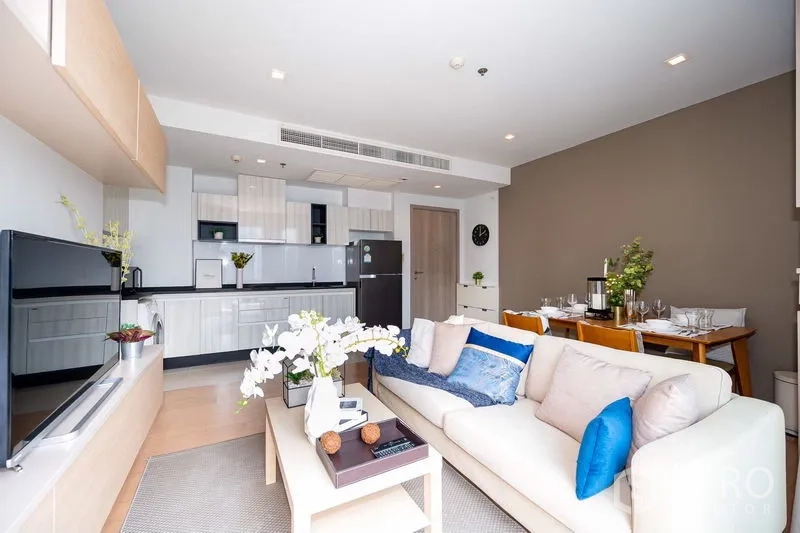 公寓 出租在Watthana, Bangkok - 起居区面向开放式厨房与电视墙及餐桌。