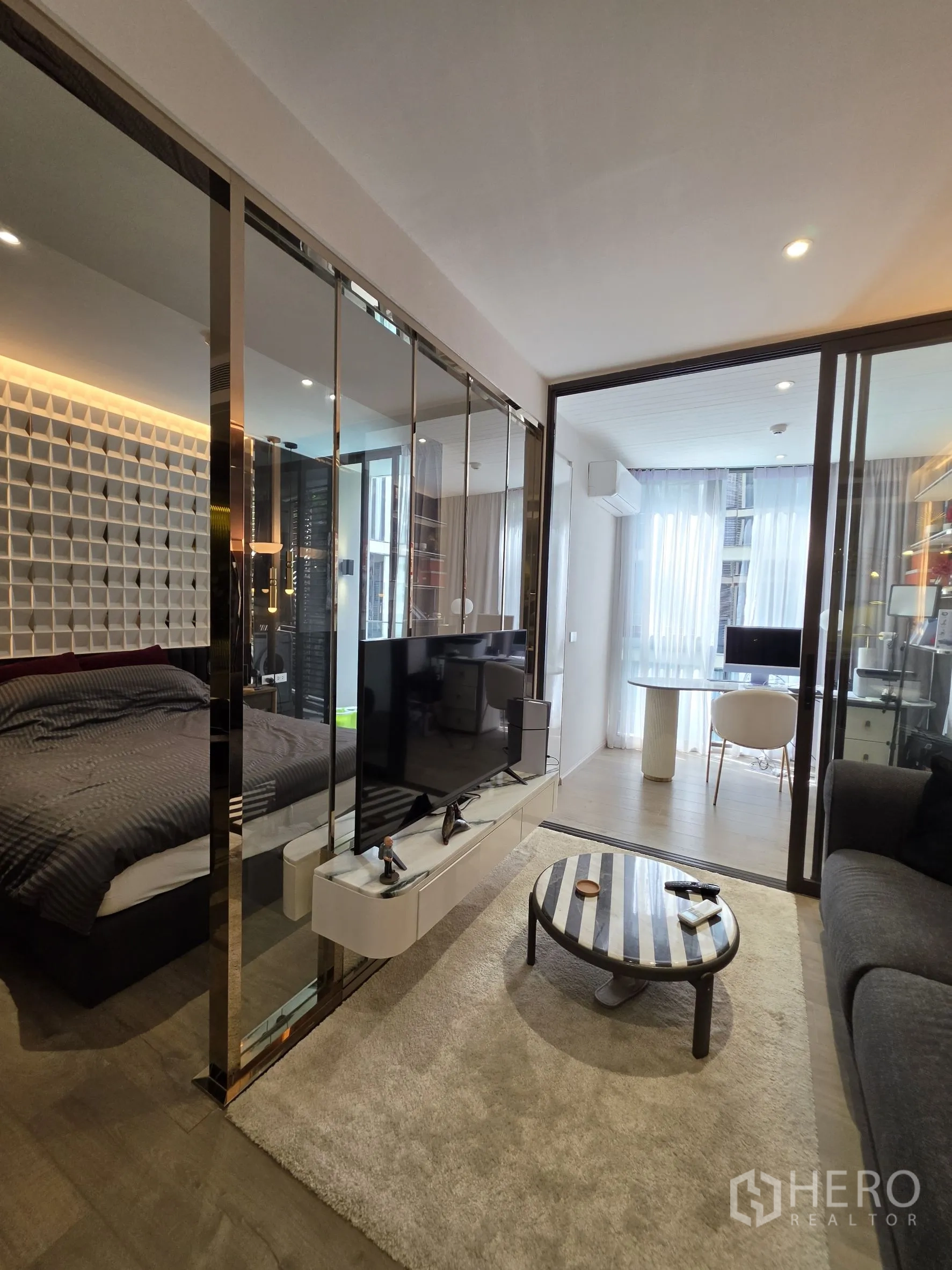 คอนโด for rent in Khlong Toei, Bangkok - พื้นที่นั่งเล่นแบบเปิดมีโซฟา ตู้ทีวี และกั้นกระจกกับห้องนอน ด้านหน้ามีมุมรับประทานอาหารสว่าง