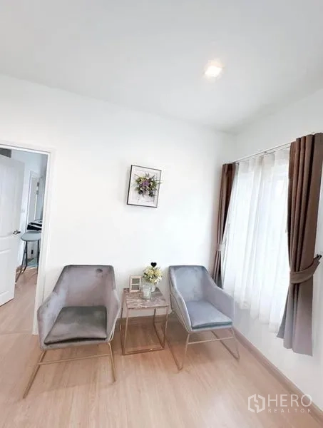 Detached House for rent in Bueng Kum, Bangkok - Upstairs sitting nook with two accent chairs beside wide windows and wood flooring.