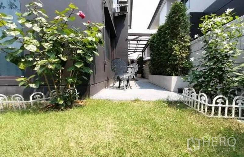 Detached House for sale in Bang Phli, Samut Prakan - Backyard patio with bistro set, walkway and landscaped plants beside the home.