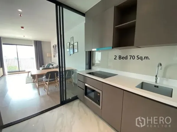 Condominium for rent in Watthana, Bangkok - Modern enclosed kitchen with built-in hob, oven and sliding glass partition opening to dining and living area.