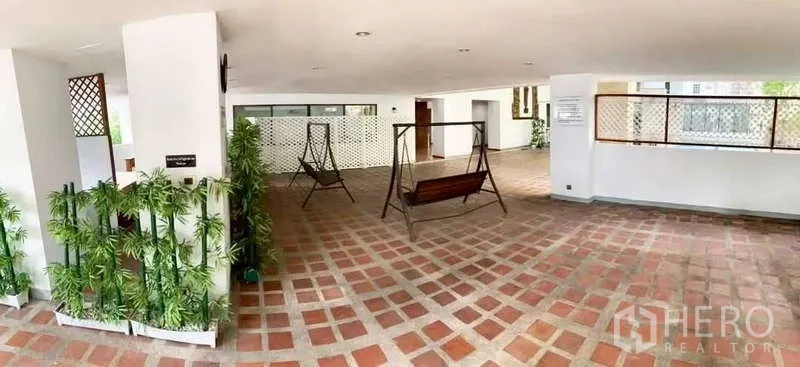 พื้นที่ขายปลีก ให้เช่าในWatthana, Bangkok - พื้นที่กึ่งเอาต์ดอร์มีหลังคาคลุม ปูพื้นกระเบื้องลายตาราง พร้อมม้านั่งชิงช้าโลหะ ต้นไม้กระถาง และเสาสีขาว เหมาะทำการค้า