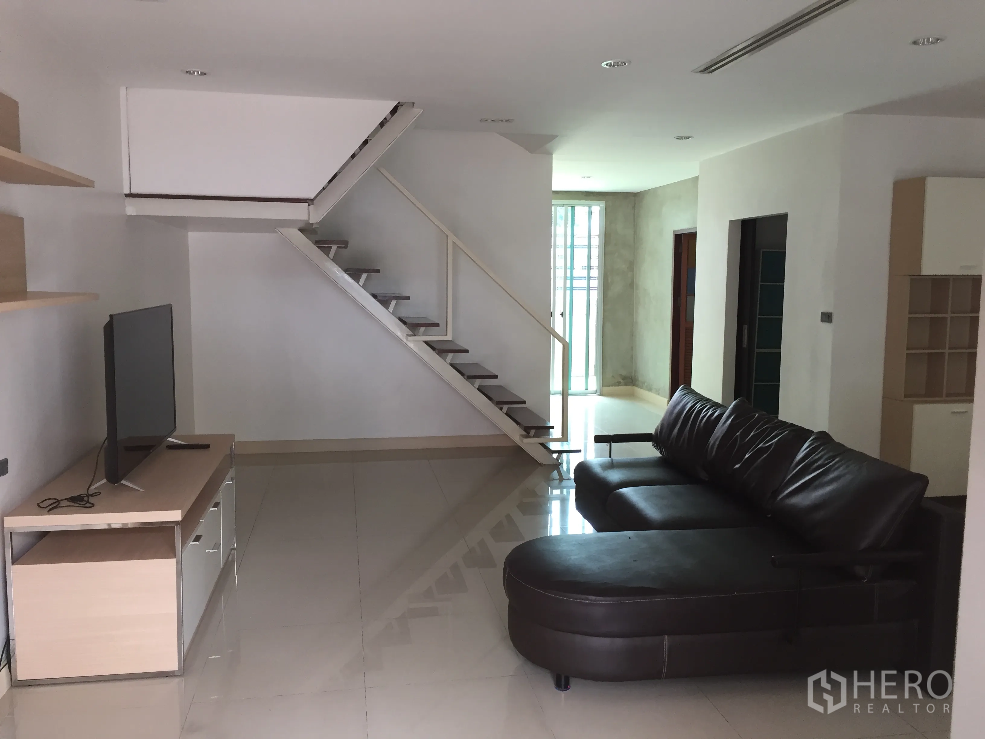 ทาวน์เฮาส์ ให้เช่าในDin Daeng, Bangkok - ห้องนั่งเล่นแบบโอเพ่นพร้อมโซฟาหนังชิ้นใหญ่ โต๊ะวางทีวี และบันไดลอยสมัยใหม่