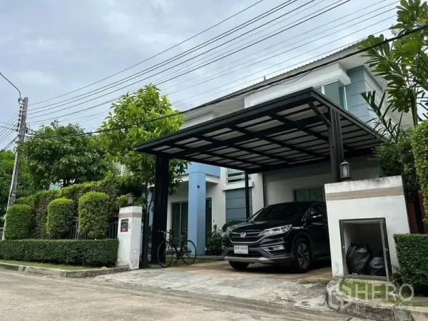 Detached House for rent in Phasi Charoen, Bangkok - Street view of the house showing carport, greenery and modern facade.