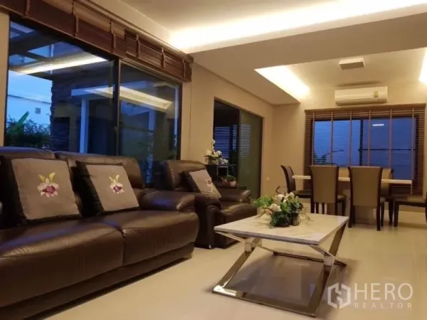 Detached House for rent in Bang Phli, Samut Prakan - Spacious living and dining room with leather sofas, recessed lighting and sliding glass doors.
