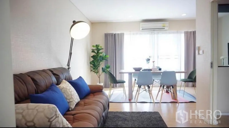 ทาวน์เฮาส์ ให้เช่าหรือขายในWang Thonglang, Bangkok - ห้องพักผ่อนอบอุ่น โซฟาสีน้ำตาลหันหน้าไปทางโต๊ะอาหารและหน้าต่างกว้างมีผ้าม่าน