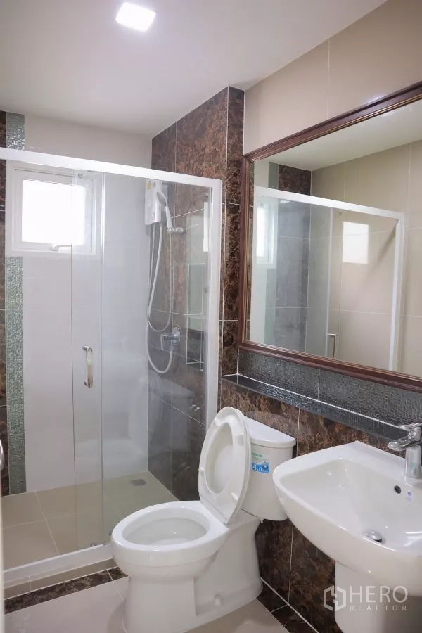Detached House for rent in Bang Phli, Samut Prakan - Second bathroom featuring glass shower enclosure, mirror and tiled walls.