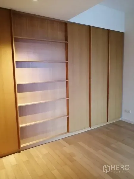 Condominium for sale in Yan Nawa, Bangkok - Bedroom with full-height wooden wardrobes and open shelving.