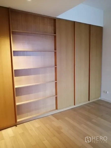 Condominium for sale in Yan Nawa, Bangkok - Bedroom with full-height wooden wardrobes and open shelving.