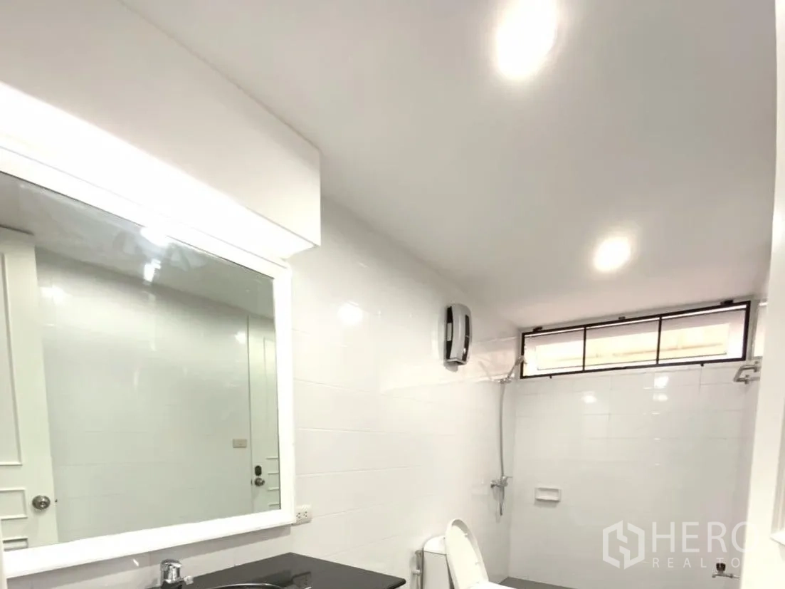 คอนโด ให้เช่าในWatthana, Bangkok - ห้องน้ำกระเบื้องสีขาวสมัยใหม่ เคาน์เตอร์อ่างล้างหน้า กระจกบานใหญ่ โถสุขภัณฑ์ และโซนอาบน้ำ