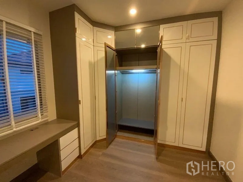 联排别墅 出租在Prawet, Bangkok - 转角嵌入式衣柜带玻璃门和书桌。