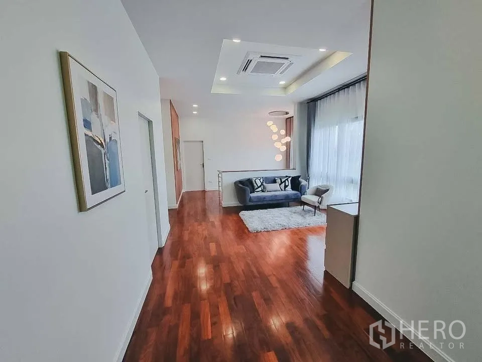 Detached House for rent or sale in Bang Phli, Samut Prakan - Spacious upstairs lounge with wood floors, recessed lighting, and a small sofa set.
