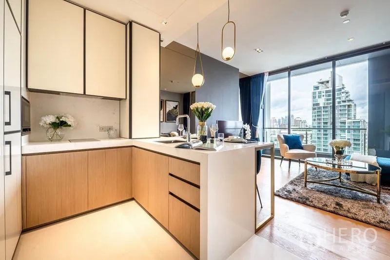 Condominium for rent or sale in Khlong Toei, Bangkok - L-shaped modern kitchen with stone countertops, pendant lights and ample storage.