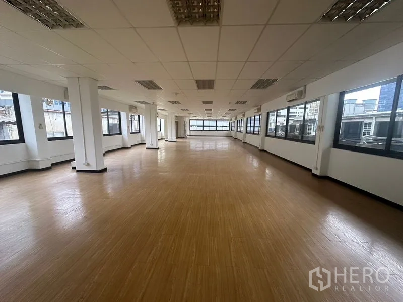 办公空间 出租在Bang Rak, Bangkok - 邦拉区开放式办公室，木纹地板、吊顶灯具与成排大窗户，采光充足。