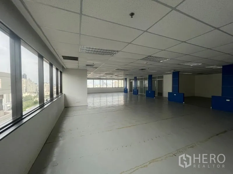 办公空间 出租 - 大开间办公区，整面窗户、蓝色立柱与城市天际线。