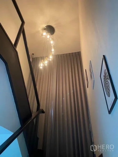 Detached House for rent in Bang Phli, Samut Prakan - Stairwell with a sleek black handrail, tall drapes and a cascading pendant chandelier.