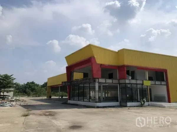 Retail Space for rent in Khlong Luang, Pathum Thani - Two-storey yellow-and-red retail warehouse with glass-fronted showroom and wide forecourt in Khlong Luang.