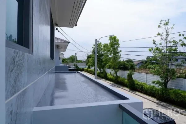 บ้าน ขายในLat Krabang, Bangkok - ระเบียงยาวมองเห็นถนนเงียบสงบมีต้นไม้เรียงราย