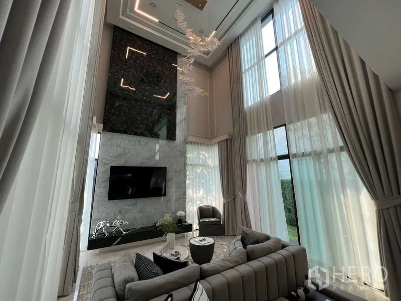 Detached House for sale in Suan Luang, Bangkok - Double-height living room with towering windows, marble feature wall and chandelier
