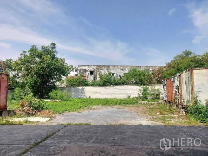 Warehouse for rent in Min Buri, Bangkok - Fenced rear yard with grass, containers and paved loading area.