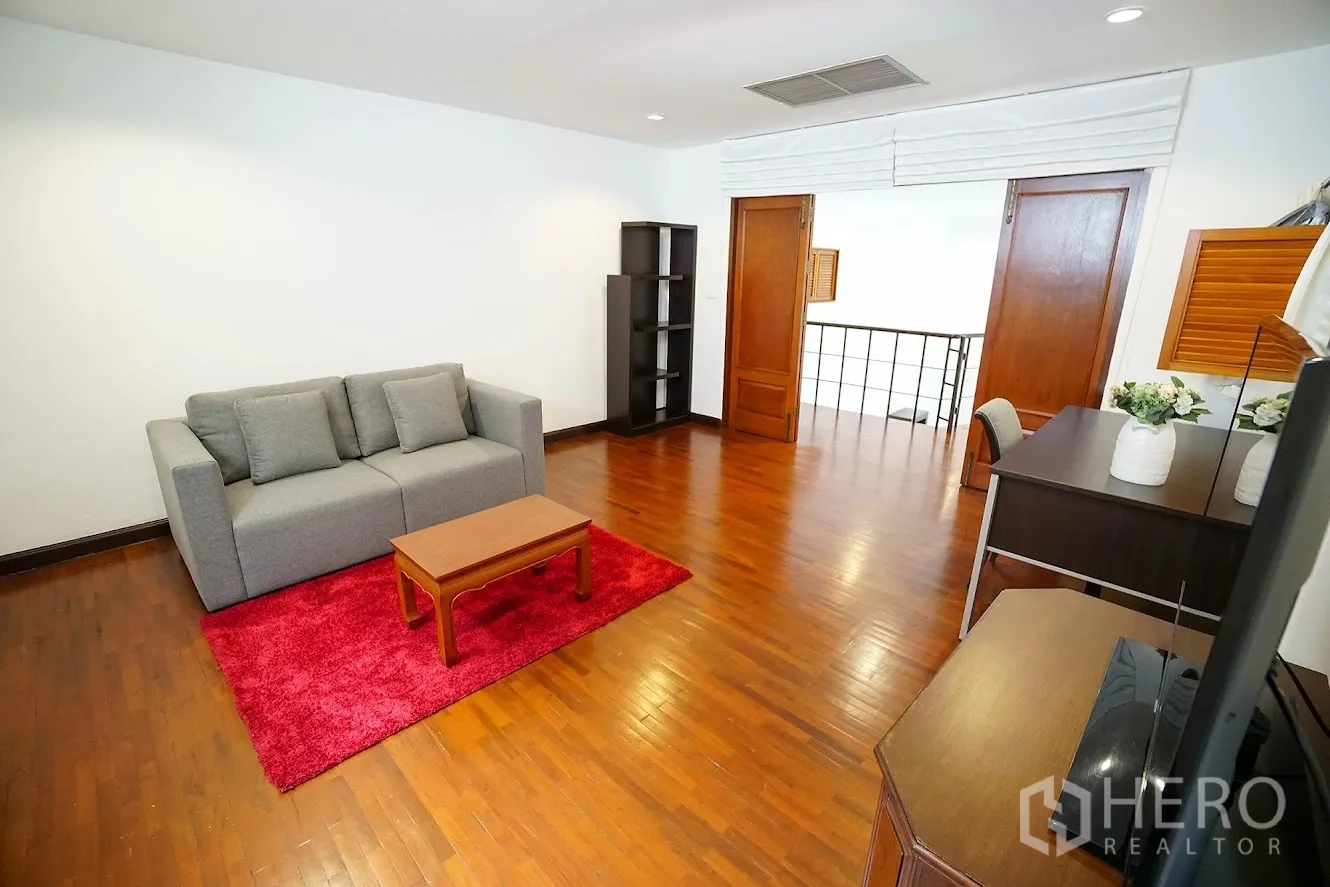 房间 出租在Watthana, Bangkok - 楼上家庭起居室，沙发、电视书桌与红色地毯。