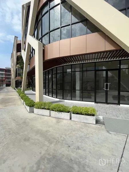 零售空间 出租在Phra Khanong, Bangkok - 现代零售立面，弧形落地玻璃与宽阔人行道及绿植花槽