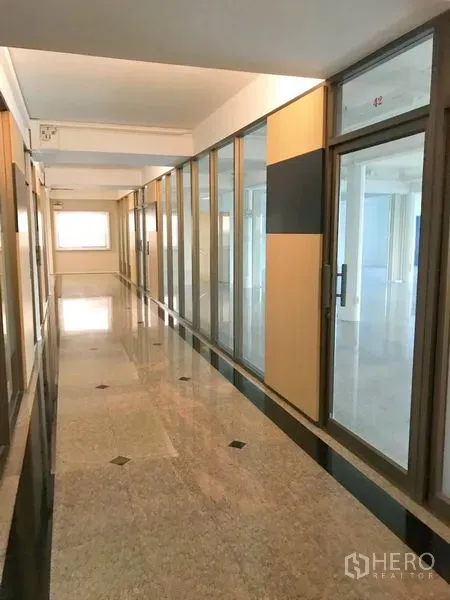 办公空间 出租在Suan Luang, Bangkok - 玻璃隔断的办公走廊，左右为独立办公室，石材地面光亮。