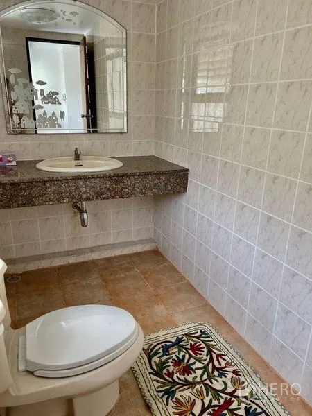 Home Office for rent - Bright tiled bathroom with toilet, mirror and a patterned rug.