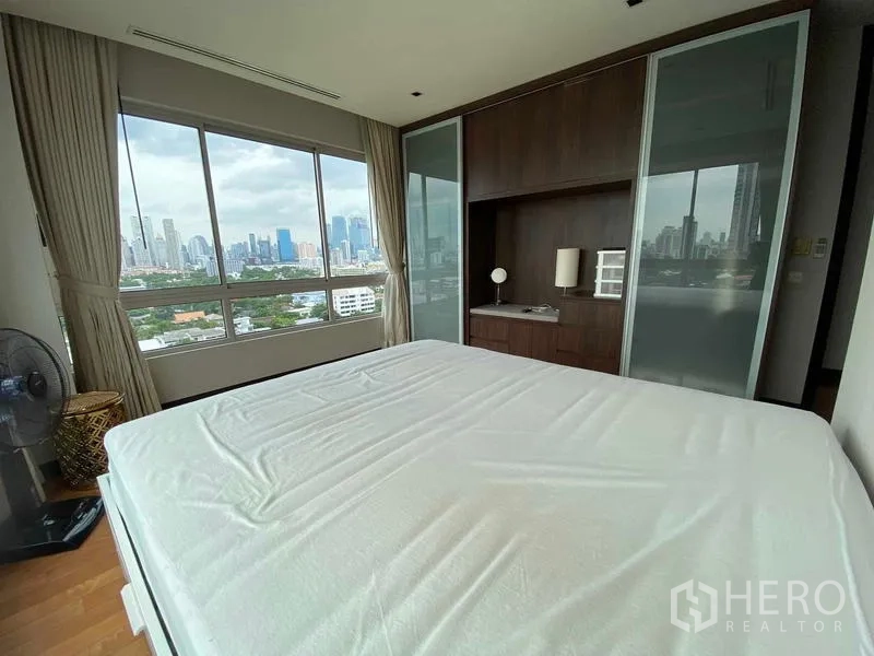 Condominium for rent in Yan Nawa, Bangkok - Primary bedroom with wall-to-wall windows, built-in wardrobe, and sweeping city skyline outlook.