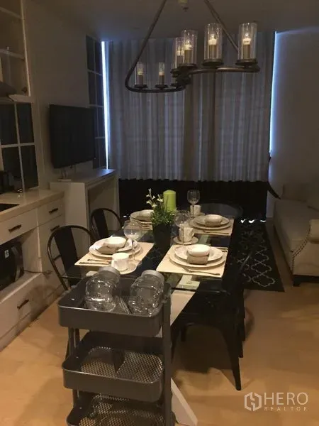 คอนโด ให้เช่าในPhaya Thai, Bangkok - พื้นที่นั่งเล่นและรับประทานอาหารแบบอบอุ่น โต๊ะกระจก ชั้นบิวท์อิน ทีวี และผ้าม่านสูง พร้อมโคมไฟระย้า