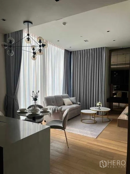 Condominium for rent - Another angle of the bright living area with sofa, rug, twin round coffee tables, and tall curtains.