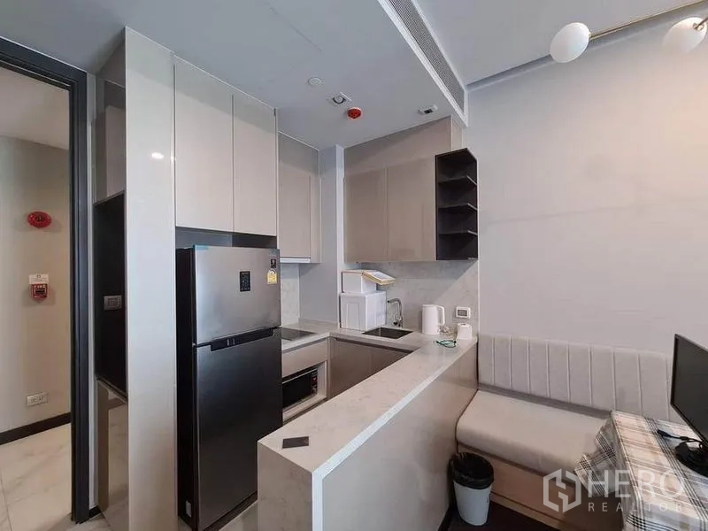 Condominium for rent in Watthana, Bangkok - Compact U-shaped kitchen with glossy cabinets and full appliances.