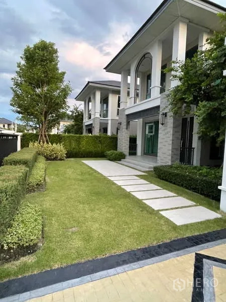 บ้าน ให้เช่าหรือขายในLat Krabang, Bangkok - สวนหน้าบ้านมีสนามหญ้า ทางเดินแผ่นทาง และแนวพุ่มตัดแต่งเรียบร้อย