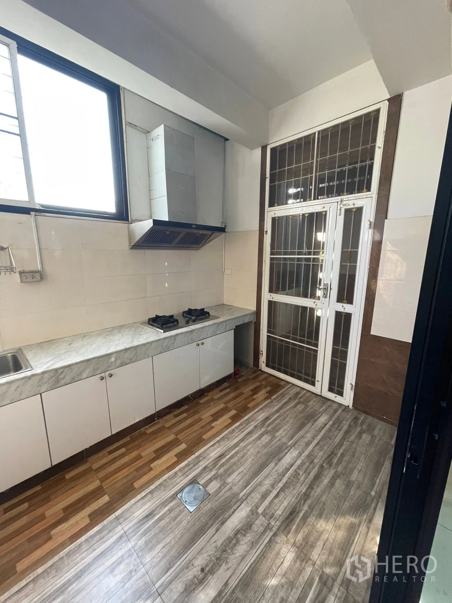 Detached House for rent or sale in Lam Luk Ka, Pathum Thani - Thai kitchen with gas hobs, extractor hood, and a metal security door.