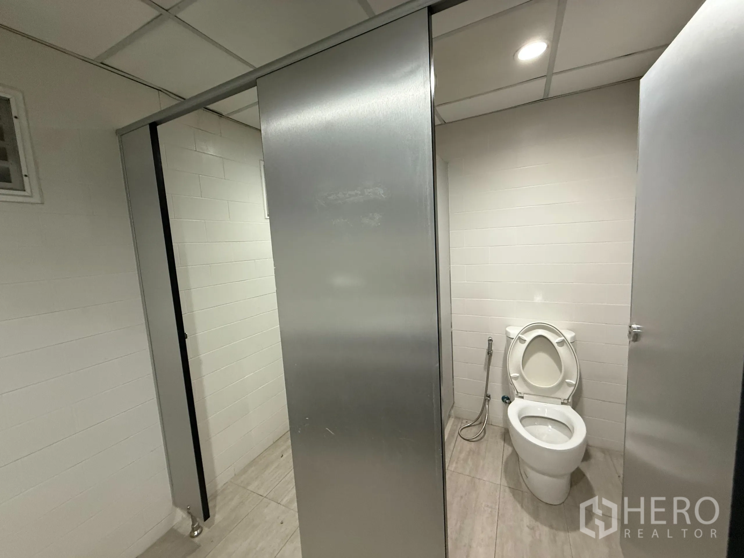 Office Space for rent in Bueng Kum, Bangkok - Toilet cubicles with white tiles and recessed ceiling lights.