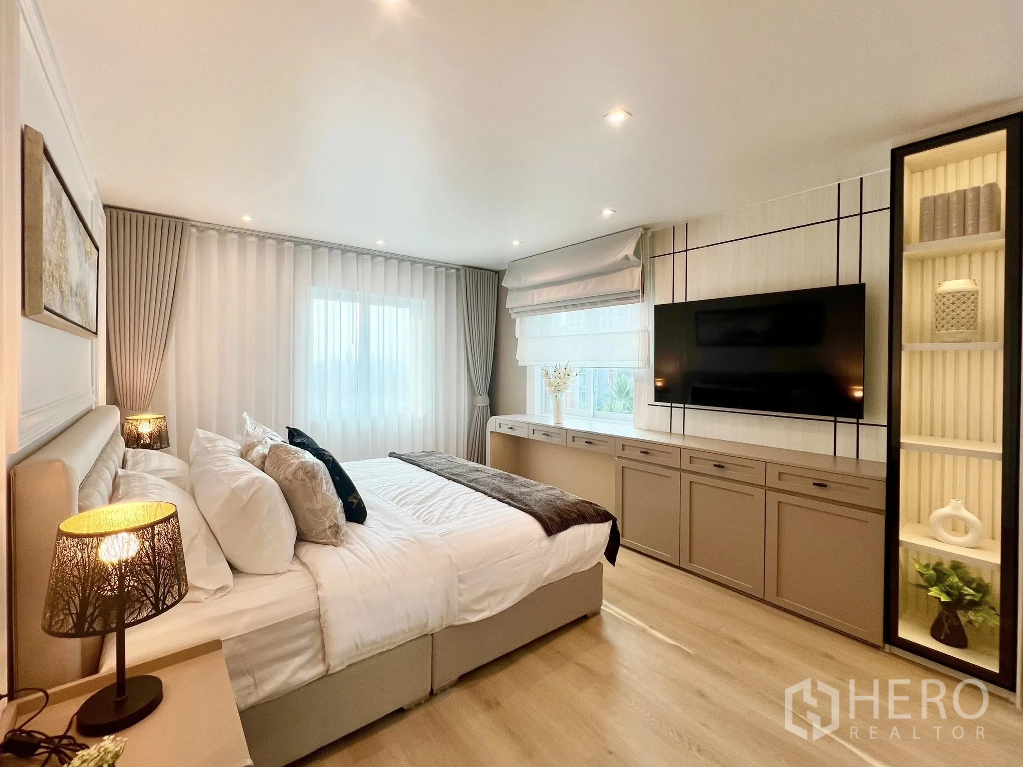 Condominium for rent or sale in Yan Nawa, Bangkok - Spacious master bedroom with media cabinetry, wall-mounted TV and illuminated display shelves.
