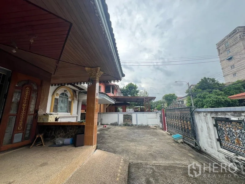 บ้าน ขายในPhra Khanong, Bangkok - ชานหน้าบ้านและลานจอดรถกว้างเชื่อมไปยังประตูรั้วลายเหล็กดัด