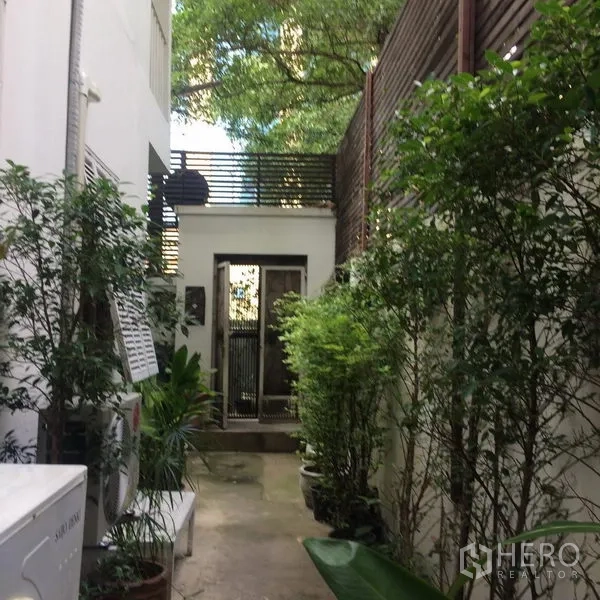 บ้าน ให้เช่าในSathon, Bangkok - ทางเดินข้างบ้านร่มรื่นด้วยต้นไม้และกระถางพาไปยังประตูทางเข้าบ้านเดี่ยวในสาทร