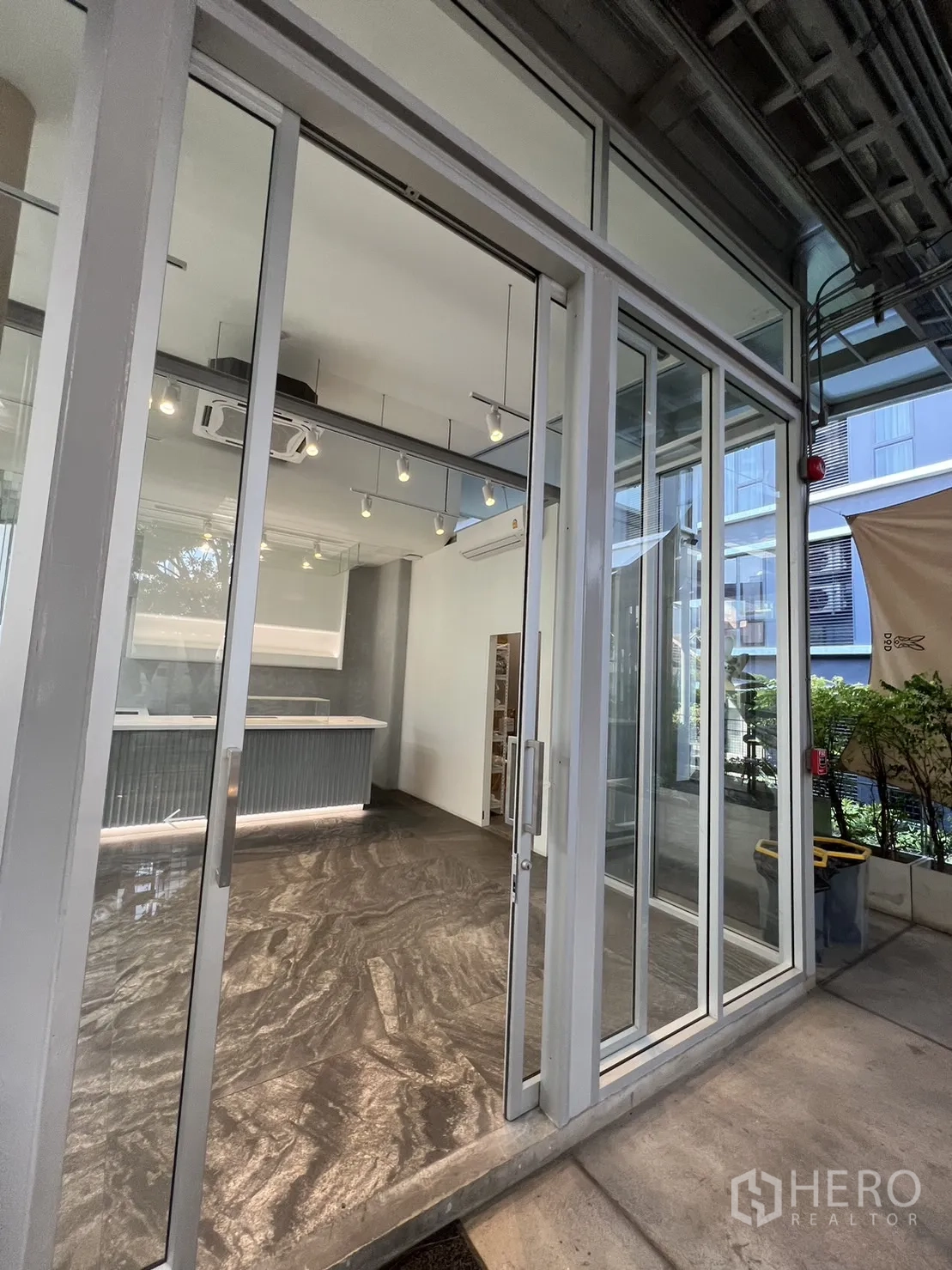 零售空间 出租在Khlong Toei, Bangkok - 宽大的玻璃门店面与有顶走道，内里现代装潢清晰可见。